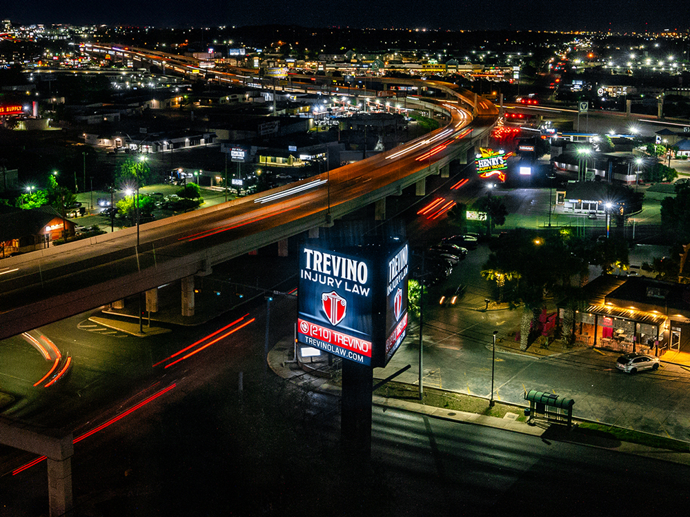 Best personal injury lawyer near me. A nighttime cityscape. In the foreground, a large lit sign reads “Trevino Injury Law – San Antonio Truck Accident Personal Injury Lawyers.”.